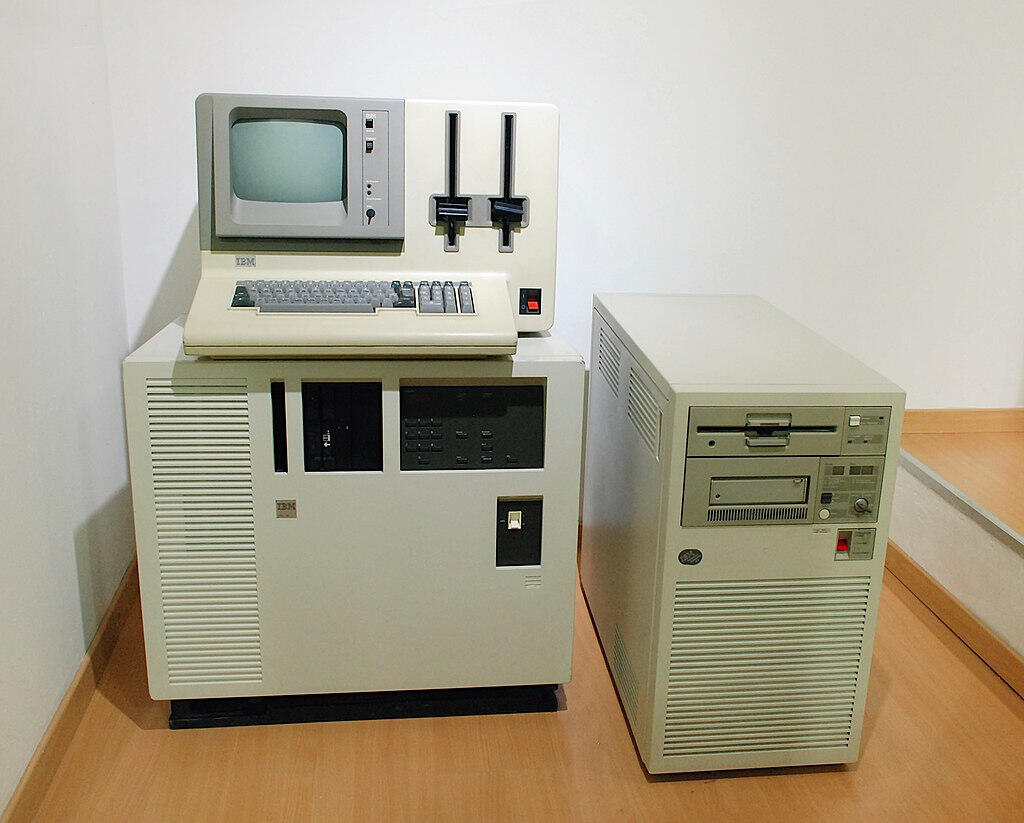IBM AS/400 de 1986, sistema de computación empresarial con pantalla monocroma, disqueteras y unidad central de gran tamaño.